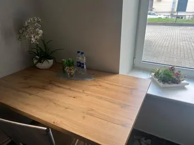 a wooden table with bottles and flowers on it at Šiauliu apartamentai in Šiauliai