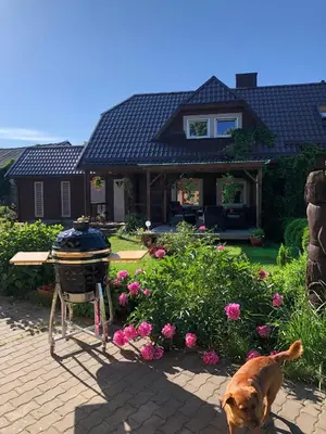 a dog standing in front of a house with a grill at Prie Ąžuolo in Zarasai