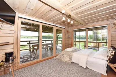 a bedroom with a bed and a balcony with a table at Vila Tauragnas in Varniškės I