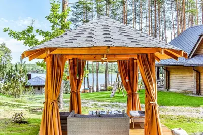 a wooden gazebo in the yard of a house at Vila Tauragnas in Varniškės I