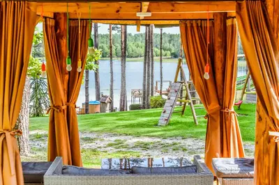 a room with orange curtains and a view of a lake at Vila Tauragnas in Varniškės I