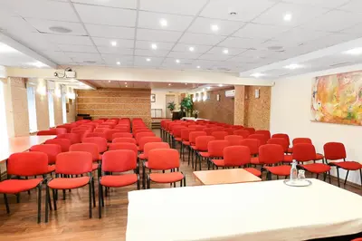 a conference room with red chairs and tables in a room at Smėlynė in Panevėžys