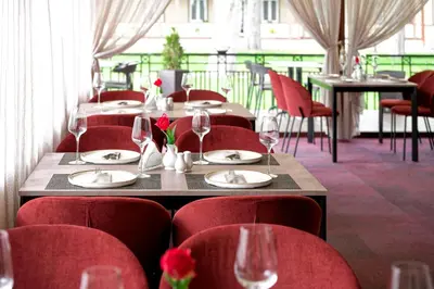 a table in a restaurant with red chairs and wine glasses at Regina in Druskininkai