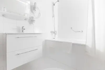 a white bathroom with a shower and a sink at Regina in Druskininkai