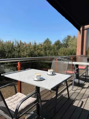 a table with two cups and chairs on a balcony at Via Baltica in Sargėnai