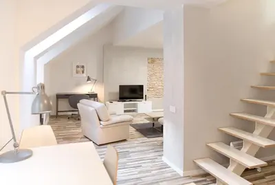a white living room with a staircase and a chair at Cathedral Sq. Apartment - Odminiu Str. in Vilnius