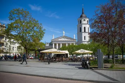 a building with a clock tower and tables and umbrellas at Cathedral Sq. Apartment - Odminiu Str. in Vilnius