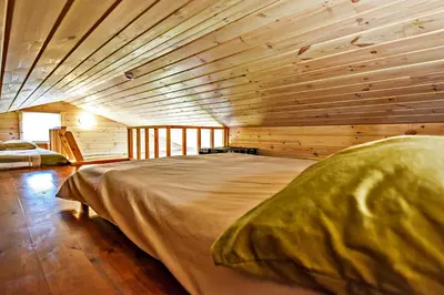 a large bed in a room with wooden walls at Mekų slėnis in Degučiai