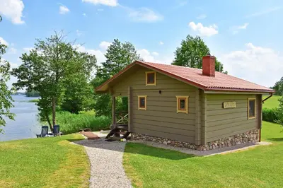 a small cabin with a red roof on the grass at Mekų slėnis in Degučiai