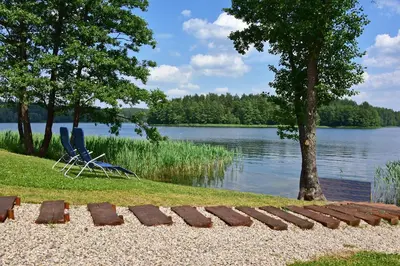 a couple of chairs sitting next to a lake at Mekų slėnis in Degučiai