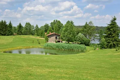 a golf course with a pond in the middle of a green at Mekų slėnis in Degučiai