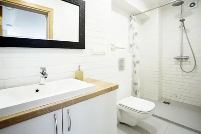 a white bathroom with a sink and a toilet at Baron's Arthouse Apartment in Vilnius