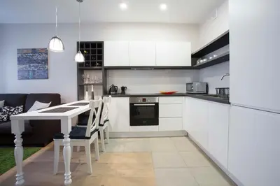 a kitchen with white cabinets and a table and chairs at Baron's Town Hall Apartments in Vilnius