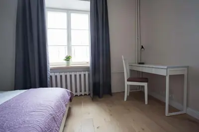 a bedroom with a bed and a desk and a window at Baron's Town Hall Apartments in Vilnius