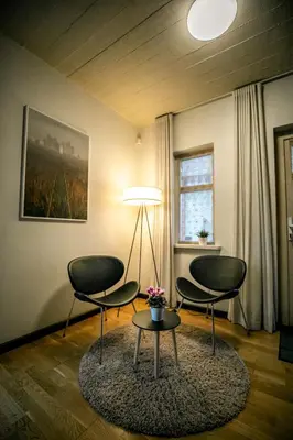 two chairs and a table in a room with a lamp at Rest ART in Anykščiai