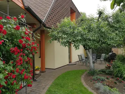 a garden with red flowers and a table and chairs at Rest ART in Anykščiai