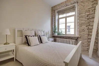 a white bedroom with a large bed and a brick wall at Town Hall Square Apartments in Vilnius