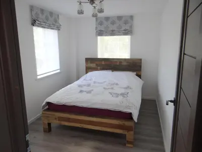 a bedroom with a bed with a wooden headboard and windows at Prie Lukos ezero in Trakai