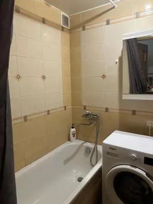 a bathroom with a tub and a washing machine at Apartamentai in Marijampolė