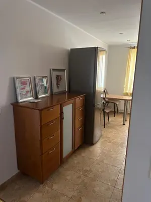 a room with a desk with a refrigerator and a table at Apartamentai in Marijampolė