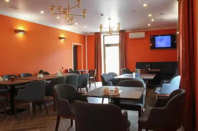 a dining room with tables and chairs and a tv at Central Hotel Radviliškis in Radviliškis
