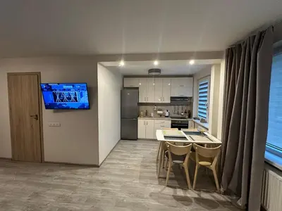 a kitchen with a table and a tv on a wall at Smiltės apartamentai in Birštonas