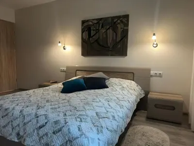 a bedroom with a bed with a blue pillow on it at Smiltės apartamentai in Birštonas