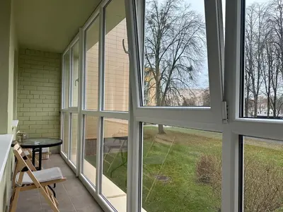 a screened porch with large windows and a table at Smiltės apartamentai in Birštonas