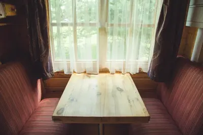 a wooden bench sitting in front of a window at Pušynėlis in Miežonys