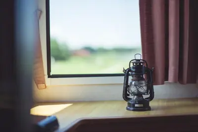 a lantern sitting on a table in front of a window at Pušynėlis in Miežonys