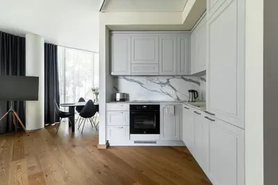 a white kitchen with white cabinets and a table at Korio Apartments, Druskininkai in Druskininkai