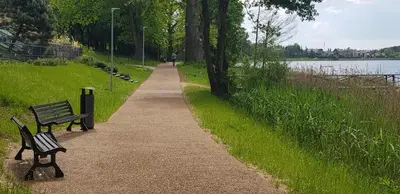 two benches on a path next to a lake at 2 kambarių apartamentai su virtuve, Trakų miesto centre in Trakai