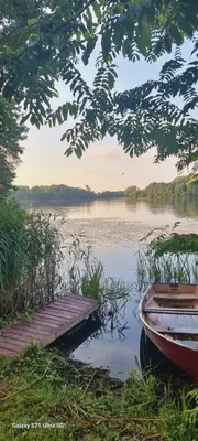 a boat sitting next to a dock on a lake at 2 kambarių apartamentai su virtuve, Trakų miesto centre in Trakai