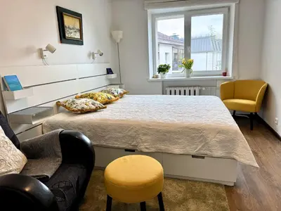 a bedroom with a large bed and two chairs at Apartment in the City center in Druskininkai