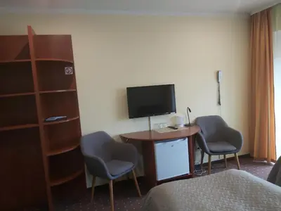 a hotel room with a desk and two chairs and a television at Hotel Green Smiltynė in Panevėžys