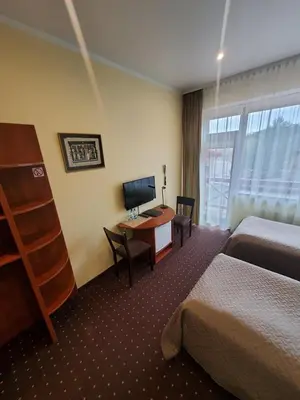 a hotel room with two beds and a desk with a computer at Hotel Green Smiltynė in Panevėžys