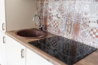 a sink in a kitchen with a mosaic wall at M.K. Apartments in Vilnius