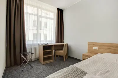 a bedroom with a bed and a desk and a window at Old Town Trio Hostel Rooms in Vilnius