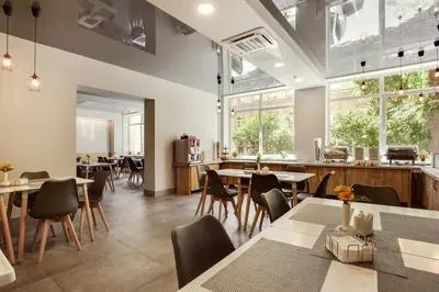 a restaurant with tables and chairs and windows at Old Town Trio Hostel Rooms in Vilnius
