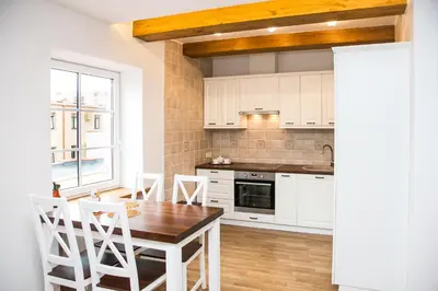 a kitchen with white cabinets and a table and chairs at Skapas Street Vilnius in Vilnius