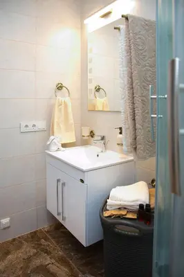 a white bathroom with a sink and a mirror at Skapas Street Vilnius in Vilnius