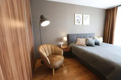 a bedroom with a bed and a chair and a lamp at Modern 2 Rooms Apartment in Kaunas