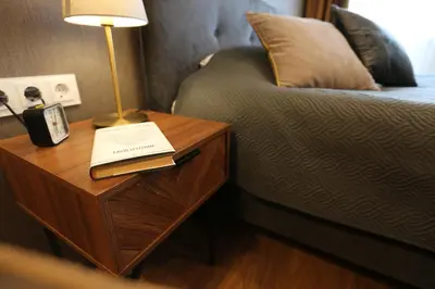 a nightstand with a lamp and a book on it next to a bed at Modern 2 Rooms Apartment in Kaunas