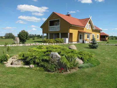 a yellow house with a garden in the yard at Homestead Sartakampis in Gipenai