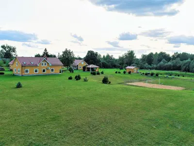 a large grassy field with a house in the background at Homestead Sartakampis in Gipenai