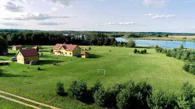 an aerial view of a house on a green field next to a river at Homestead Sartakampis in Gipenai