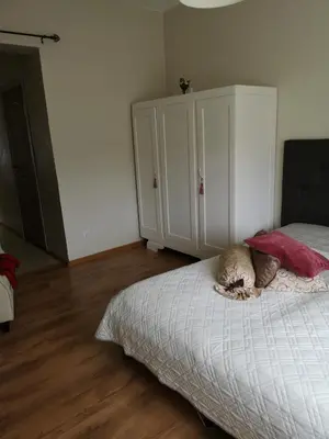 a bedroom with a bed and a white cabinet at Jaukus butas Šiaulių miesto centre in Šiauliai