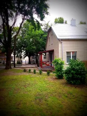a white house with a red door in a yard at Jaukus butas Šiaulių miesto centre in Šiauliai