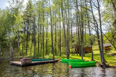 a group of green boats sitting on a lake at Ažuluokesos sodyba in Molėtai