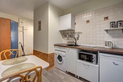 a kitchen with a washing machine and a table with chairs at Vidos Apartamentai in Vilnius